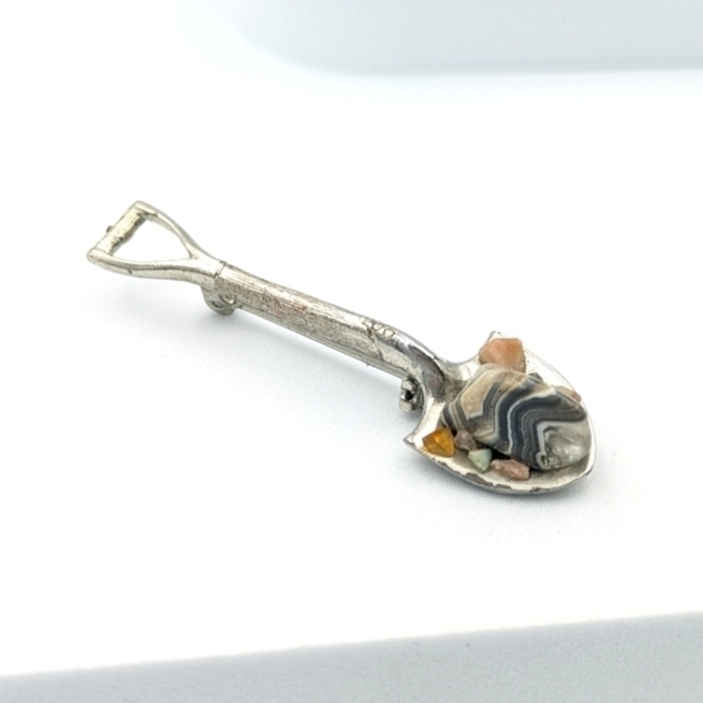 Vintage brooch pin of a shovel with polished stones